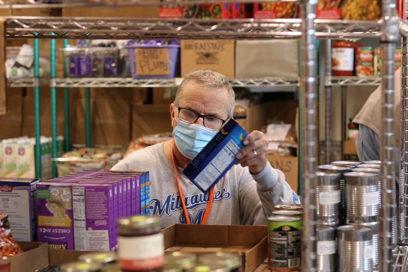 A man wearing a mask holds a box of food ensuring safety while providing sustenance