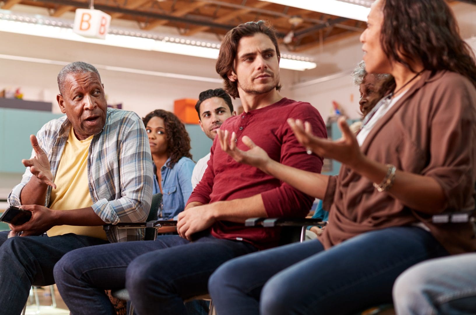 Group of people sitting in chairs talking.