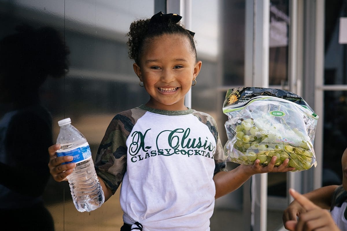 Girl holding a bag of grapes and smiling